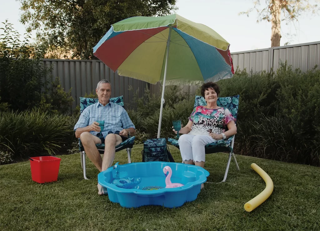 Elderly couple sitting by a portable pool